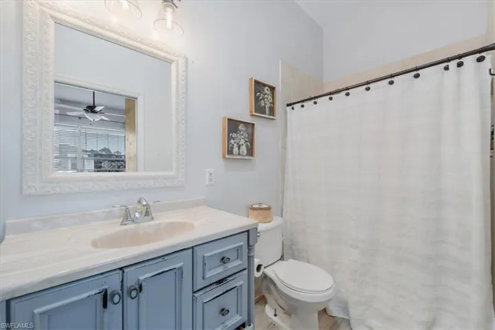Full bathroom featuring toilet, vanity, and ceiling fan