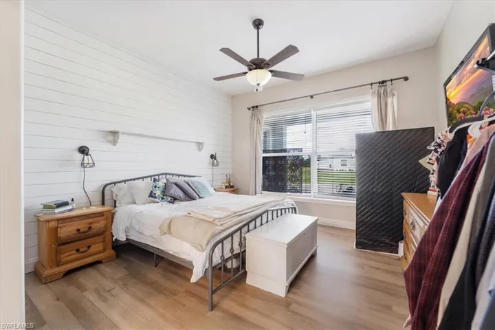 Bedroom with wood walls, wood finished floors, ceiling fan, and baseboards