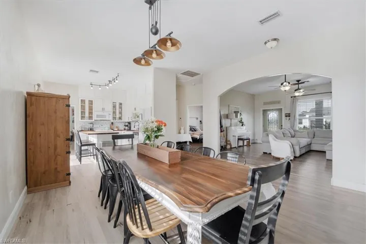 Dining room featuring visible vents, baseboards, arched walkways, ceiling fan, and light wood-style floors
