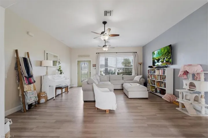 Living room featuring visible vents, baseboards, a ceiling fan, and wood finished floors