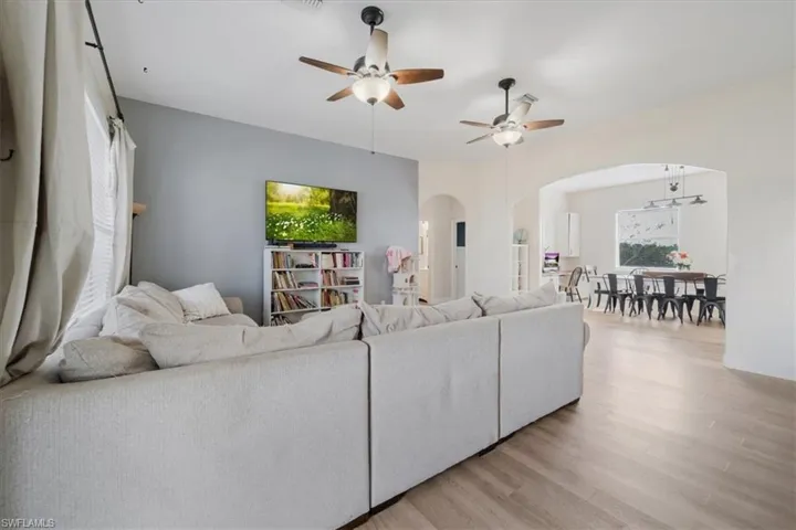 Living area with ceiling fan, light wood-type flooring, and arched walkways