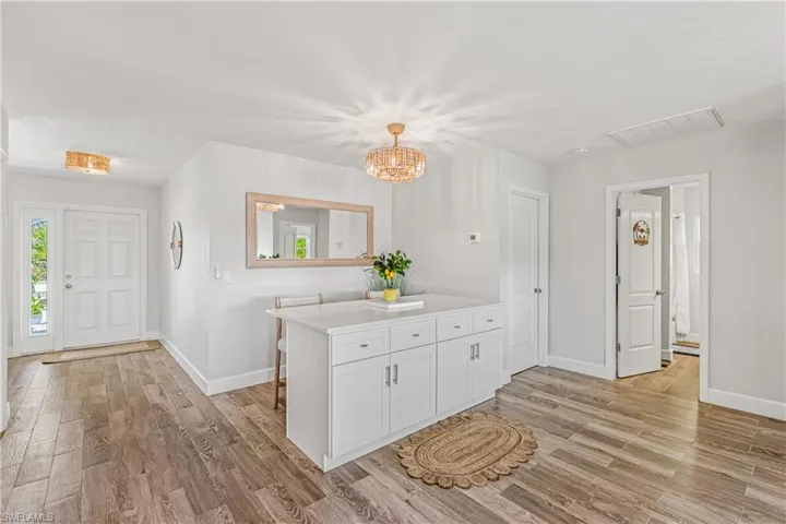 Kitchen featuring a breakfast bar, light wood finished floors, a chandelier, and a peninsula