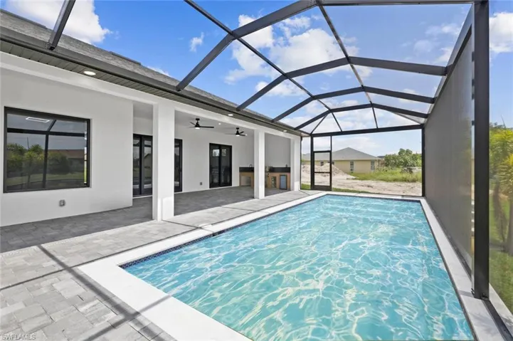 View of pool with ceiling fan, glass enclosure, and a patio