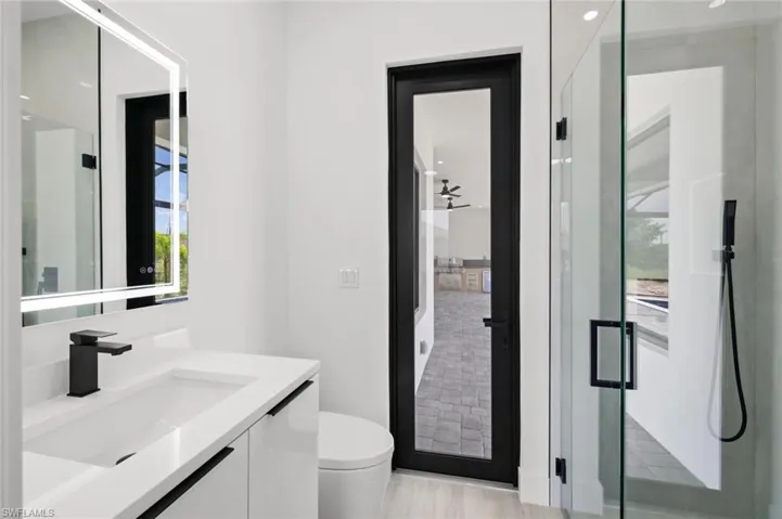 Bathroom with toilet, an enclosed shower, and vanity