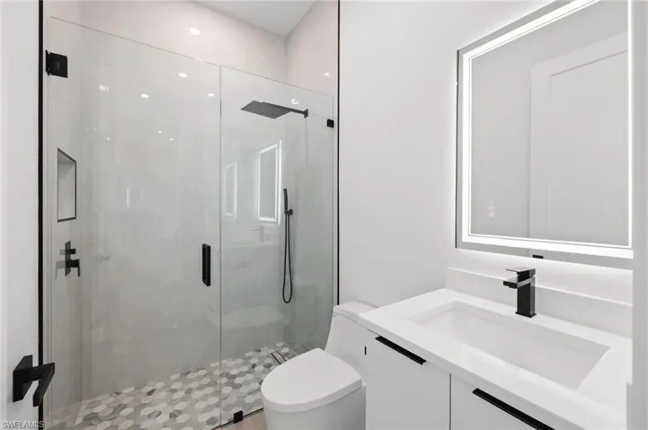 Bathroom with an enclosed shower, toilet, and vanity