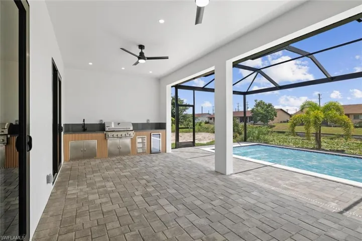 View of pool with ceiling fan, sink, and grilling area