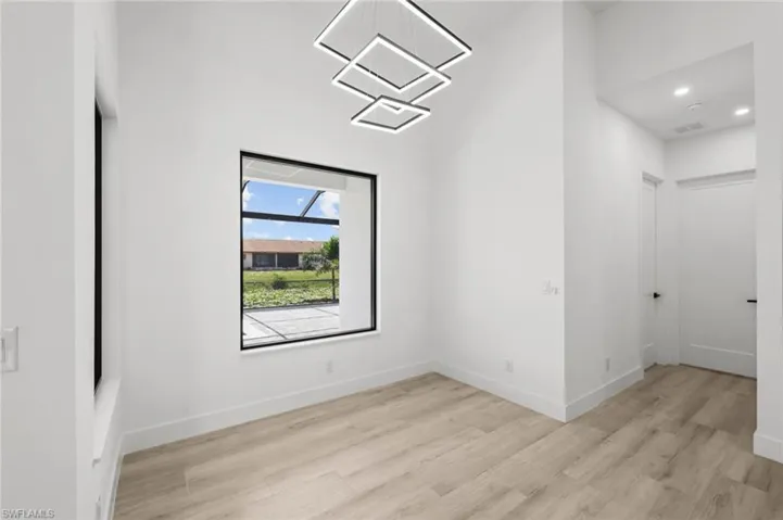 Spare room featuring a chandelier and light wood-type flooring