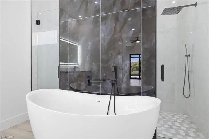 Bathroom with tile walls, separate shower and tub, and wood-type flooring