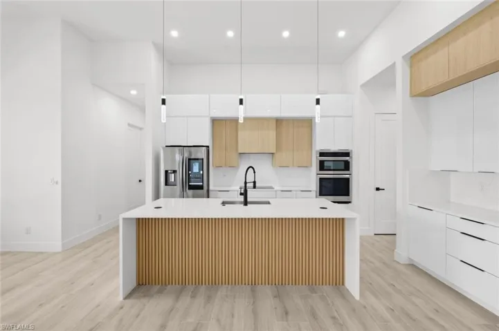 Kitchen with sink, light hardwood / wood-style flooring, an island with sink, stainless steel appliances, and white cabinets