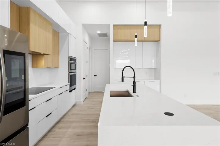 Kitchen featuring sink, pendant lighting, white cabinets, and light wood-type flooring