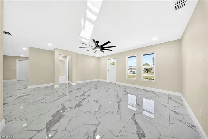 Large format polished tile flooring, recessed lighting, ceiling fan, multiple windows, and neutral wall tones