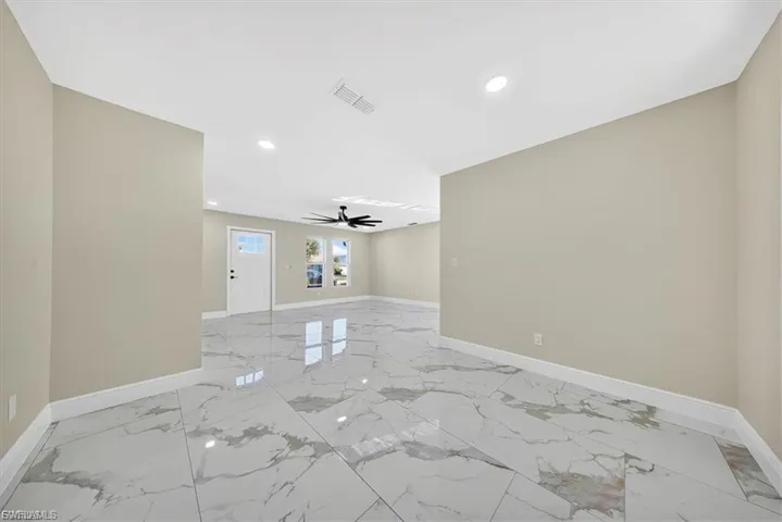 Porcelain tile flooring, recessed ceiling lighting, light gray wall paint, white trim, and a white paneled entry door