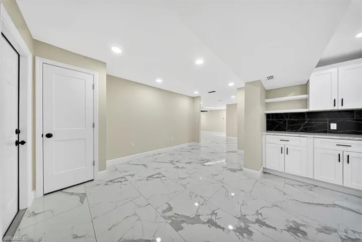 Recessed lighting illuminating a spacious room with light-toned walls and large format tile flooring