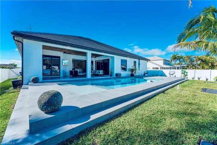 Back of house featuring a fenced in pool, a fenced backyard, a ceiling fan, a yard, and a patio area