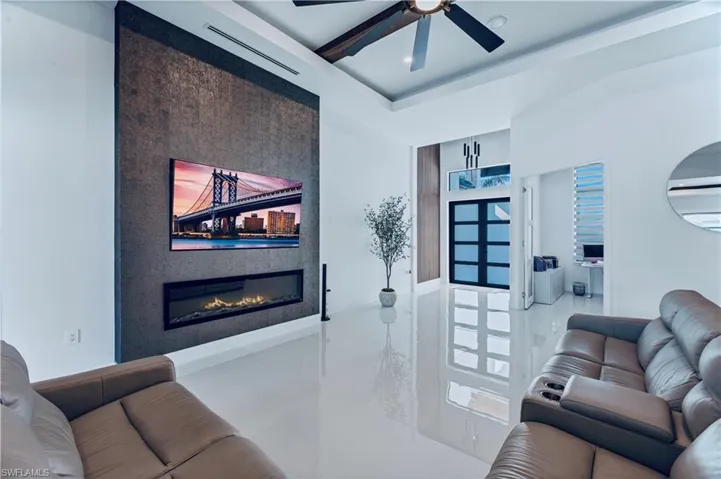 Living area with visible vents, a glass covered fireplace, and a ceiling fan