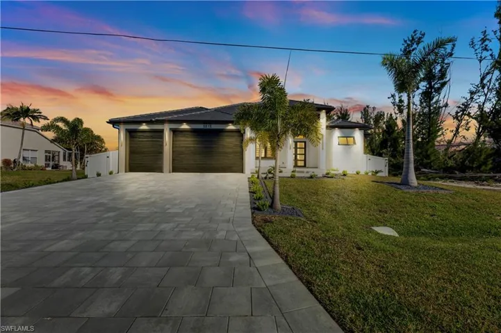 Modern home with stucco siding, a garage, a front yard, and decorative driveway