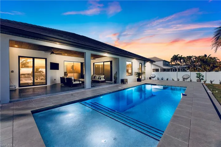 Pool at dusk with an outdoor hangout area, a patio, a fenced in pool, a fenced backyard, and a ceiling fan