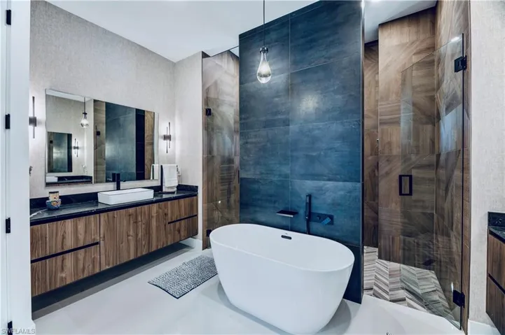 Bathroom featuring a soaking tub, vanity, a stall shower, and tile walls