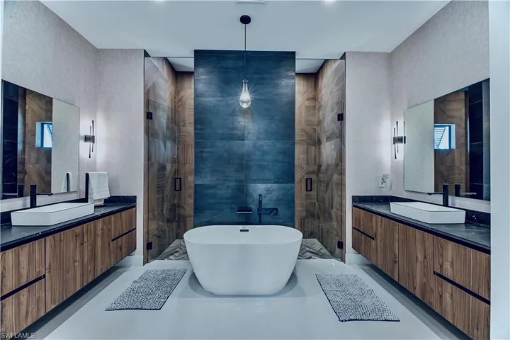 Full bathroom featuring a stall shower, a freestanding bath, a sink, and two vanities