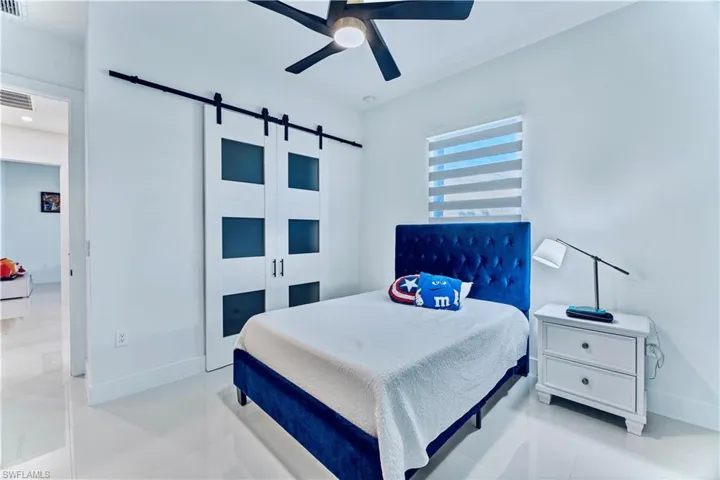 Bedroom with baseboards, visible vents, a barn door, and a ceiling fan