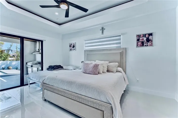 Bedroom with a ceiling fan, baseboards, access to exterior, and a tray ceiling