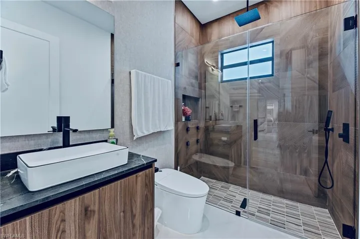 Bathroom featuring toilet, vanity, and a shower stall