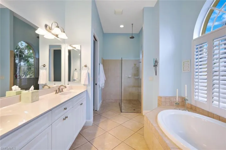 Large primary bathroom featuring a dual vanity, separate shower and tub, and a wealth of natural light.