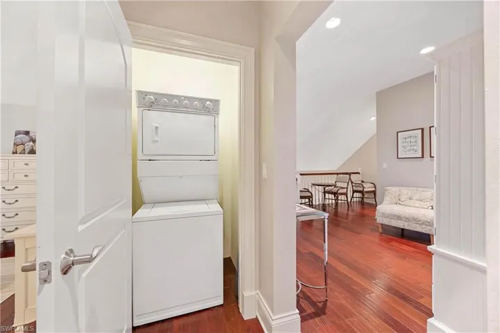 Laundry area featuring recessed lighting, dark wood-style flooring, and stacked washing machine and dryer