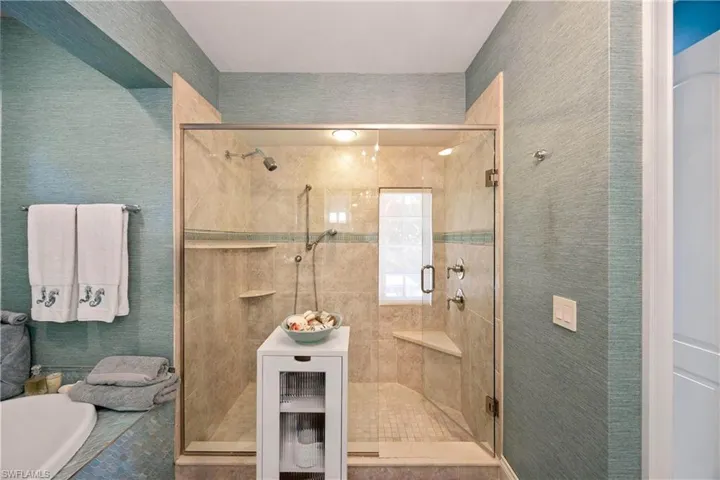 Full bath with wallpapered walls, a shower stall, and a bath