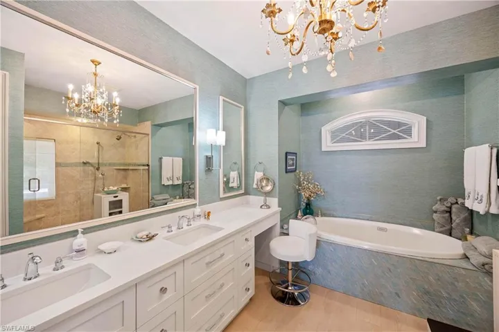 Bathroom featuring hanging lights, double vanity, and a bath