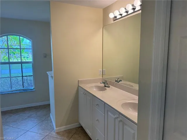 Primary bath with double vanity and light tile patterned flooring