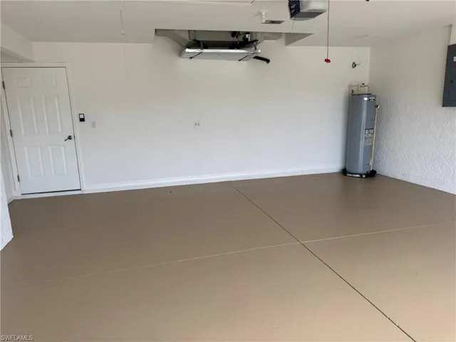 Garage with a garage door opener, water heater, and electric panel