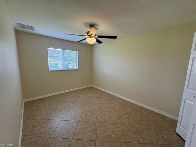 Guest bedroom 1 featuring light tile patterned floors, a textured ceiling, and ceiling fan