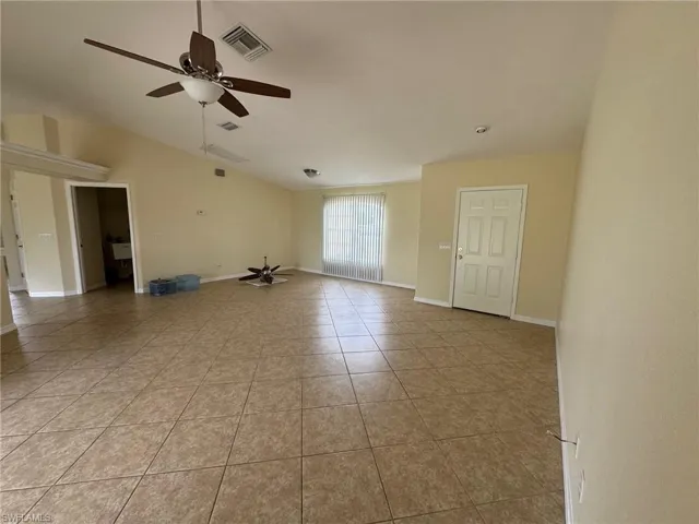 Living room featuring lofted ceiling, a ceiling fan, and light tile patterned flooring