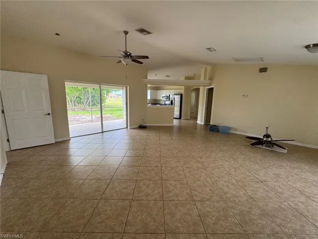 Living room with a ceiling fan, high vaulted ceiling, and tile patterned floors