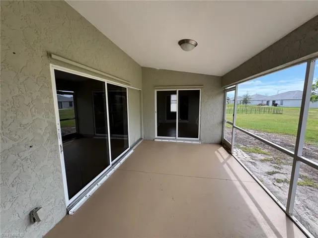 Unfurnished sunroom with vaulted ceiling and a patio