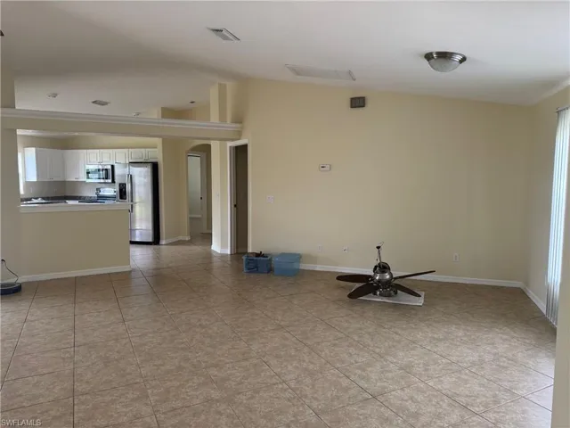 living room with vaulted ceiling, plenty of natural light, arched walkways, and light tile patterned floors