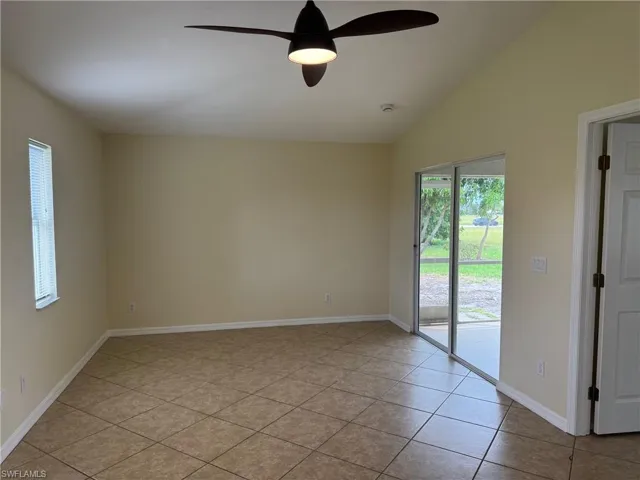 Primary bedroom featuring lofted ceiling, a ceiling fan, and light tile patterned flooring