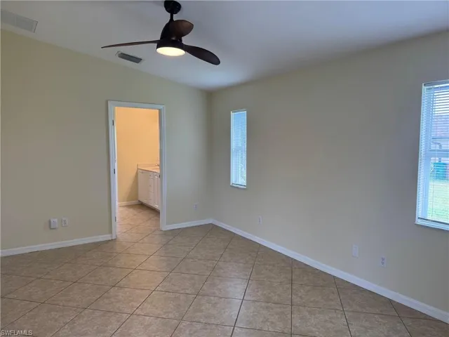 Primary bedroom featuring a ceiling fan, light tile patterned flooring, and healthy amount of natural light
