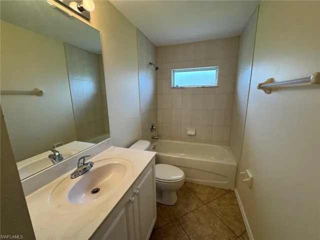 Bathroom with shower / washtub combination, vanity, and dark tile patterned flooring