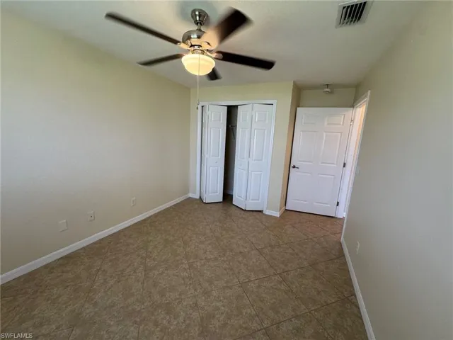 Guest bedroom 1 with ceiling fan, a closet, and dark tile patterned flooring