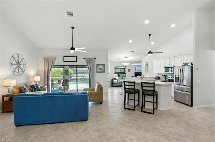Living room featuring plenty of natural light, high vaulted ceiling, ceiling fan, and light tile patterned floors