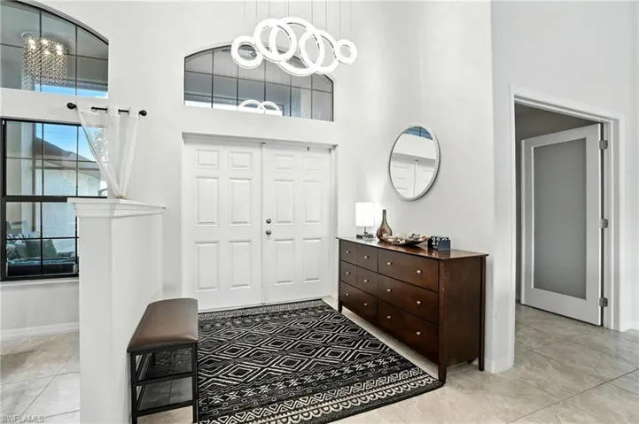 Living room featuring high vaulted ceiling, a ceiling fan, and light tile patterned floors