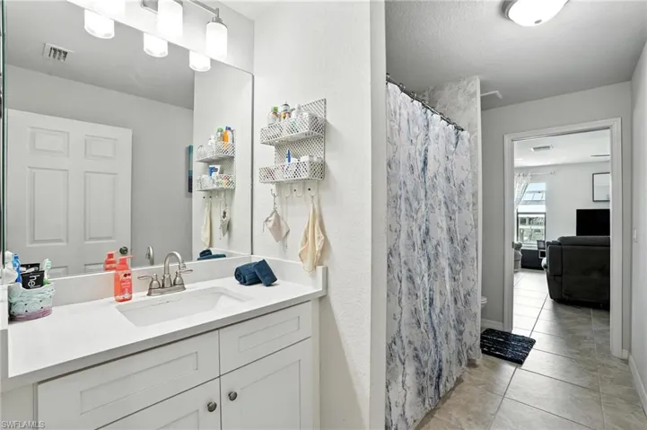 Full bath featuring a marble finish shower and vanity