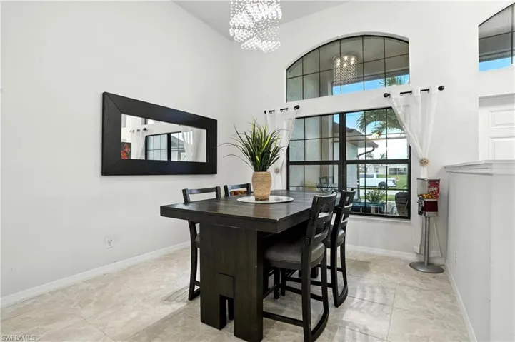 Kitchen with stainless steel appliances, backsplash, a towering ceiling, light countertops, and white cabinets