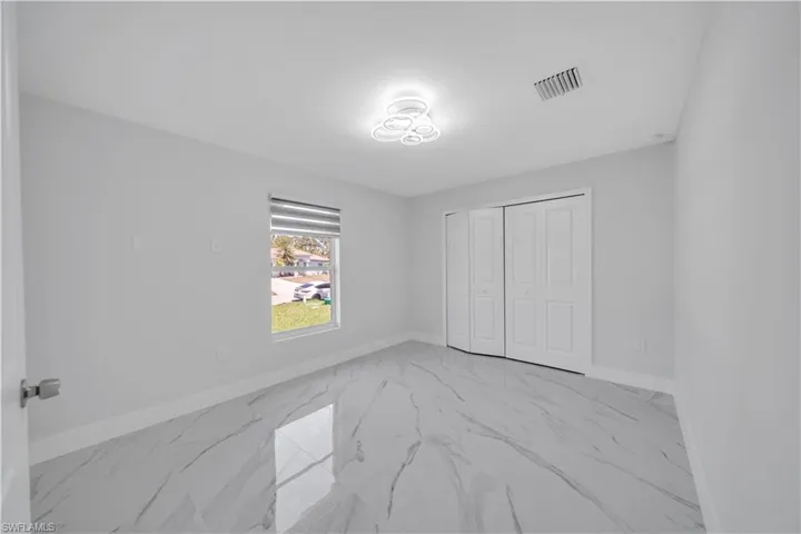 Bedroom featuring baseboards, marble finish floor, visible vents, and a closet