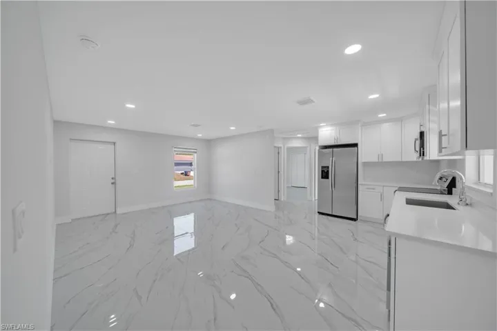 Kitchen with light countertops, a sink, stainless steel appliances, marble finish floor, and recessed lighting