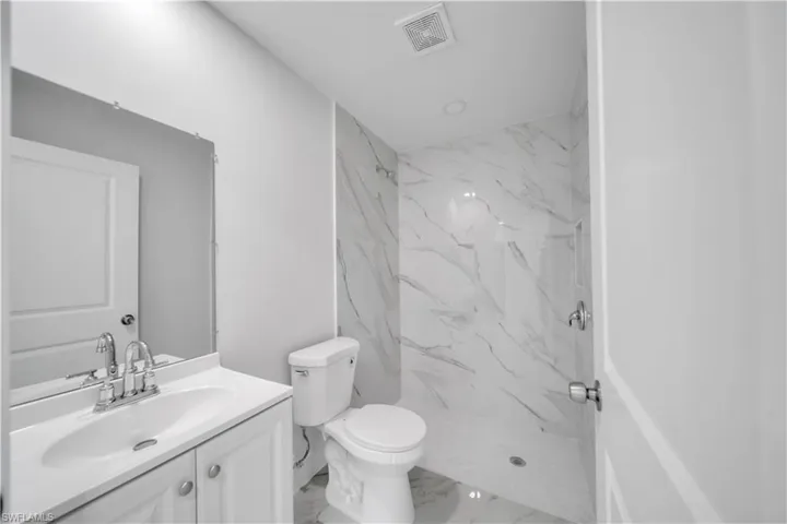 Full bath with visible vents, marble finish floor, a marble finish shower, toilet, and vanity