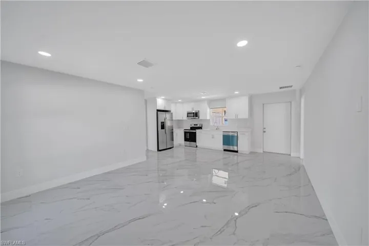 Unfurnished living room featuring marble finish floor, baseboards, visible vents, and recessed lighting