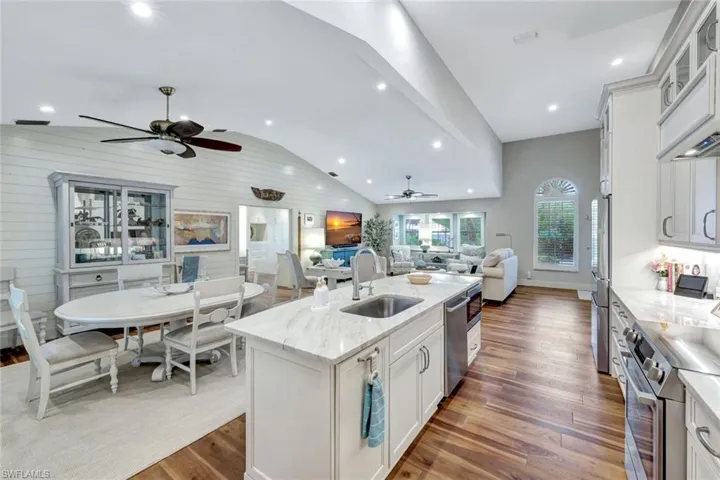 Kitchen featuring ceiling fan, stainless steel appliances, open floor plan, wood finished floors, and lofted ceiling